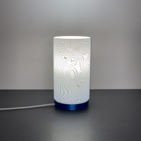 Luminária Curvas de Nível acesa, com textura inspirada em mapas topográficos, feita em PLA sustentável