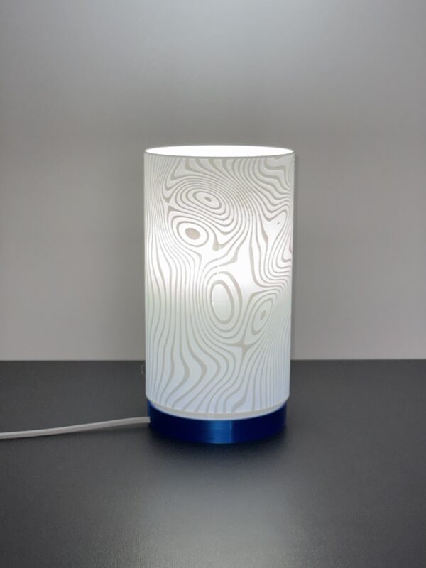 Luminária Curvas de Nível acesa, com textura inspirada em mapas topográficos, feita em PLA sustentável